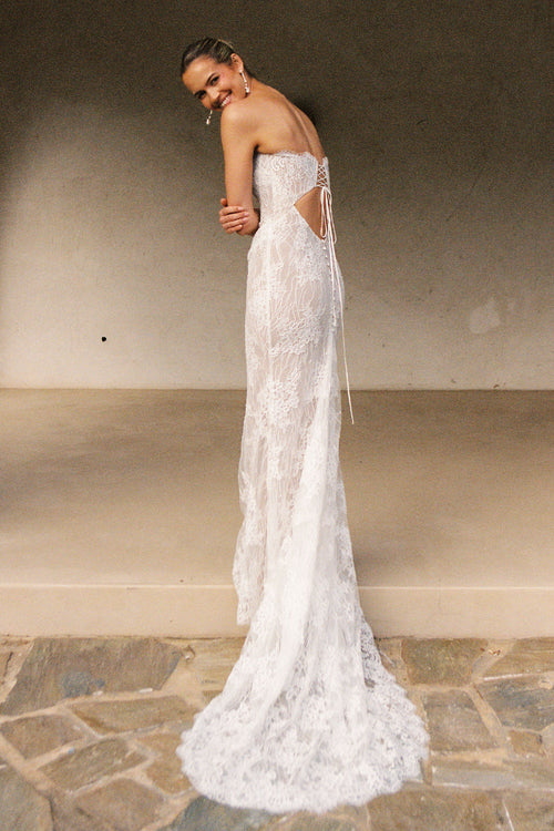 A woman wearing a strapless white lace wedding gown with a long train_XS_