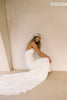 A woman wearing a strapless white wedding gown with a draped bodice and floor-length silhouette_xs_