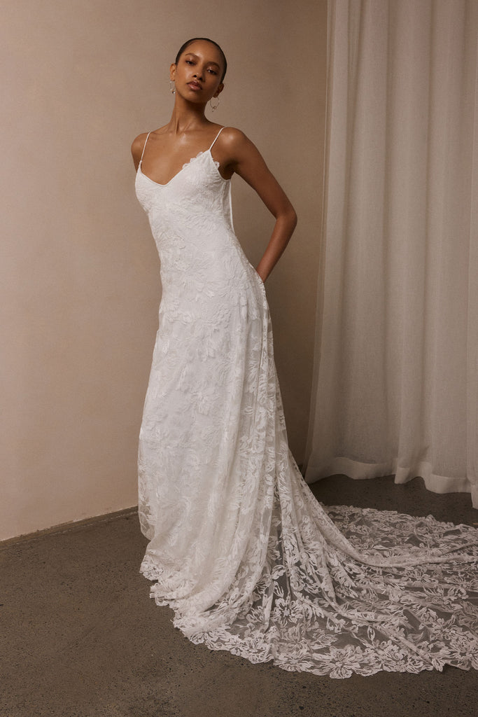 woman wearing a white lace backless dress with thin straps and delicate chain jewellery across her back