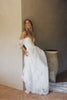 A woman wearing a white off-the-shoulder lace wedding gown with a deep V neckline and a full layered skirt_XS_