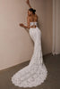 A woman wearing a strapless white lace wedding gown with a long train