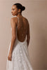 woman wearing a white lace backless dress with thin straps and delicate chain jewellery across her back