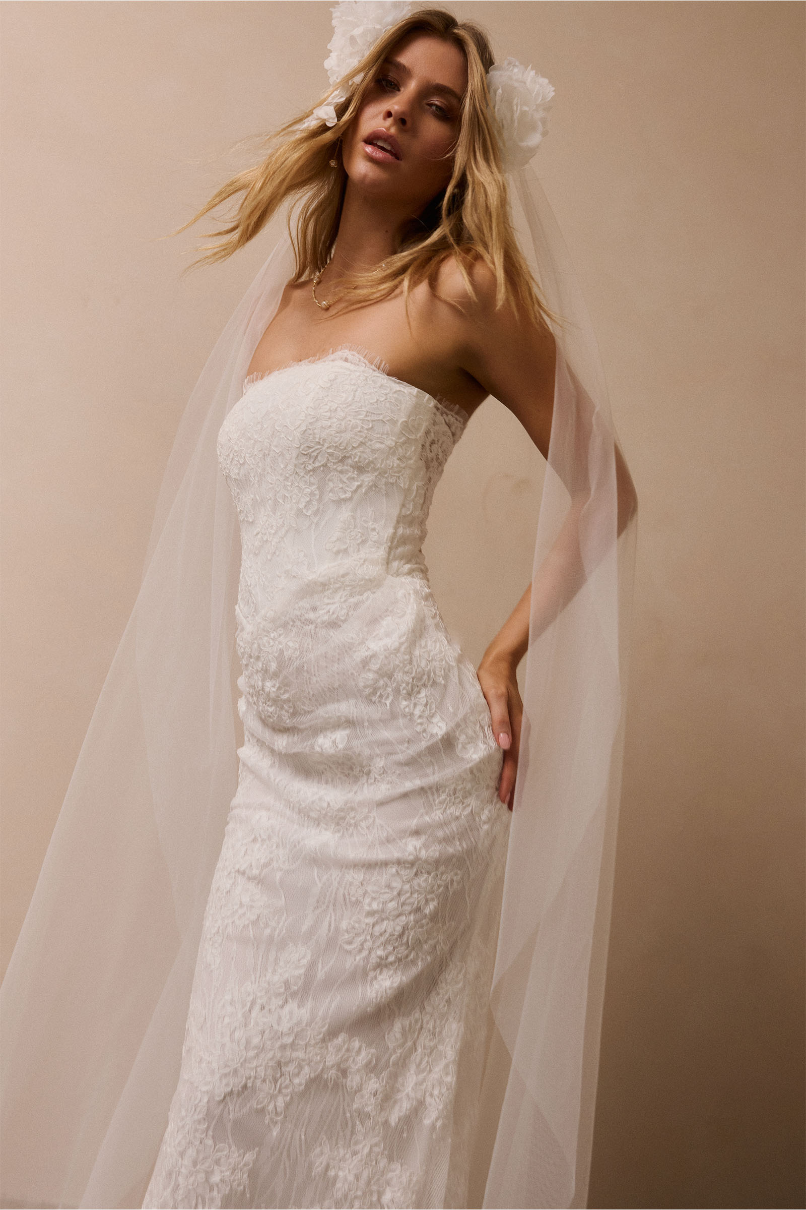 A woman wearing a strapless white lace wedding gown with a long train_XS_