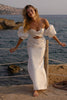 Woman in a satin wedding dress standing by the sea_XS_