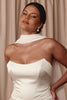 Woman wearing a white dress with pearl earrings