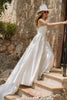 Woman walking up stairs in a satin wedding dress and hat_XS_