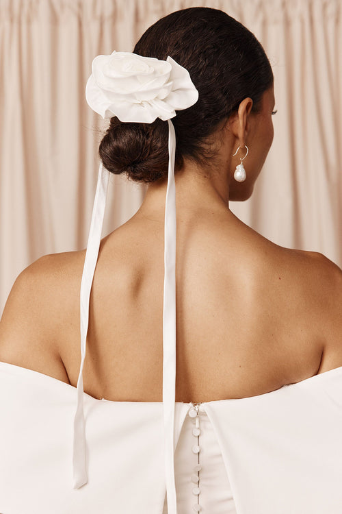 Woman wearing a white floral bridal hairpiece