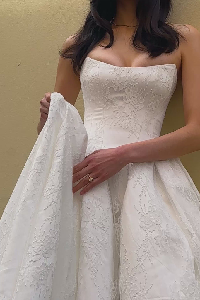 Woman wearing a lace basque waist wedding dress adjusting the skirt