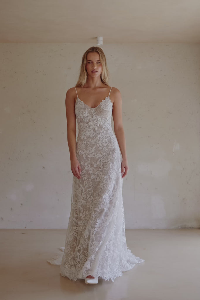 Video of a woman wearing a white lace backless dress with thin straps and delicate chain jewellery across her back_XS_